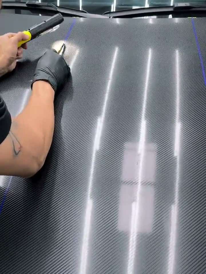 Film being fitted to a Weissach-style carbon hood on a Porsche 718 GT4