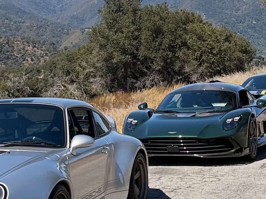 A silver Porsche and the Aston Martin Valhalla on a canyon road