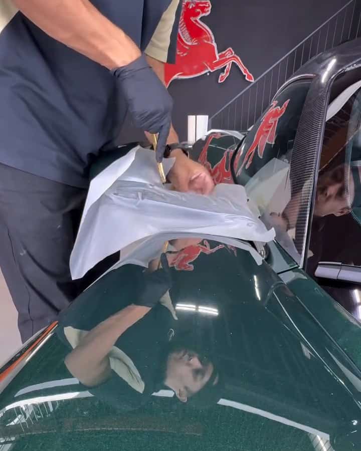Gloved hands working a sheet of Autobahn film on the Valhalla's bodywork