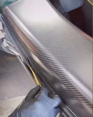 A gloved hand pressing film onto the Valhalla's matte carbon