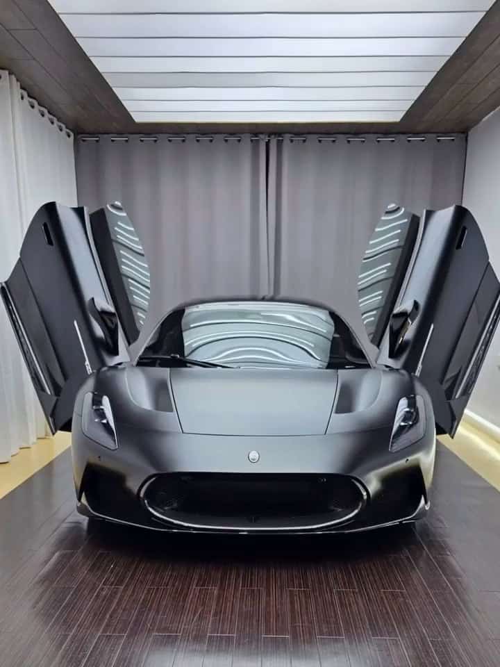 Maserati MC20 in a matte finish with its butterfly doors up in the shop's photo bay